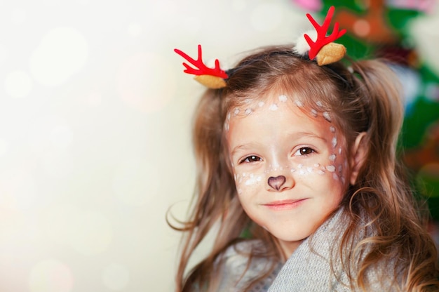 Ein Mädchen mit dem Make-up eines Weihnachtskitzes lächelt