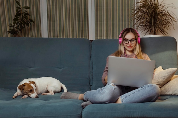 Ein Mädchen mit einem Hund, das einen Film auf einem Laptop mit Kopfhörern anschaut Haustiere und Tierfreunde für Menschen