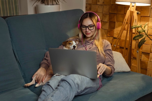 Ein Mädchen mit einem Hund, das einen Film auf einem Laptop mit Kopfhörern anschaut Haustiere und Tierfreunde für Menschen