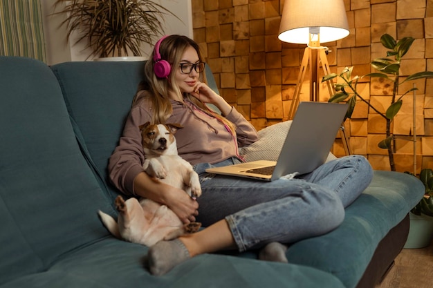 Ein Mädchen mit einem Hund, das einen Film auf einem Laptop mit Kopfhörern anschaut Haustiere und Tierfreunde für Menschen