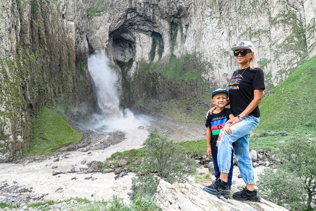 Ein Mädchen mit einem Kind auf dem Hintergrund des Wasserfalls KarakayaSu in Russland