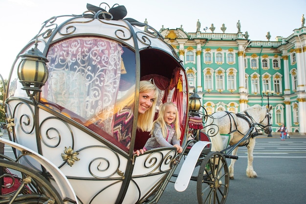 Ein Mädchen mit einem Kind in einer alten Kutsche auf dem Schlossplatz in St. Petersburg