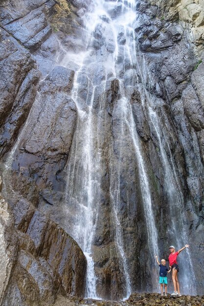 Ein Mädchen mit einem Kind vor dem Hintergrund des AbaiSu-Wasserfalls KabardinoBalkarien Juni 2021