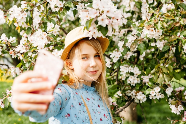 Ein Mädchen mit einem Telefon in der Hand macht Fotos von sich selbst, Selfies