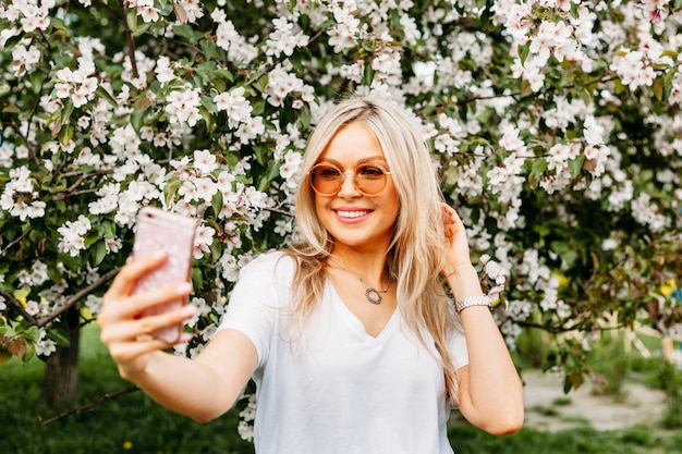 Ein Mädchen mit einem Telefon in der Hand macht Fotos von sich selbst, Selfies