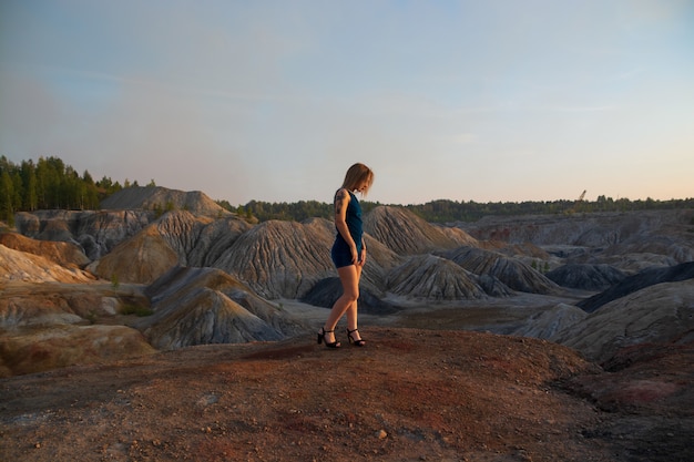 Ein Mädchen mit einer Tätowierung in einem blauen Kleid auf einem Berg. Steinbruch und Berge aus Ton