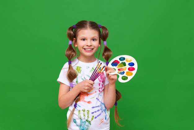 Ein Mädchen mit Farben auf grün isoliertem Hintergrund Kreativitätskurse für Kinder in Malerei mit Aquarellen und Gouache