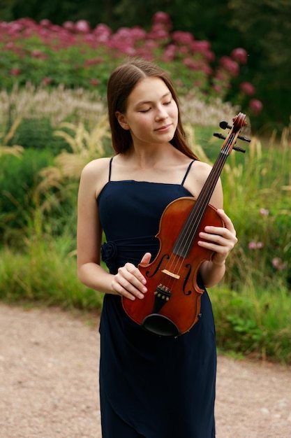 Ein Mädchen mit Geige steht im Sommer im Park