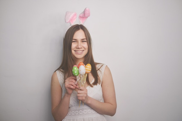 Ein Mädchen mit Hasenohren in ihren Händen hält Ostereier auf weißem Hintergrund das Konzept von Ostern