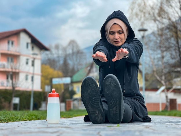 Ein Mädchen mit Hijab trainiert frühmorgens Eine muslimische Frau in Sportkleidung dehnt sich im Freien