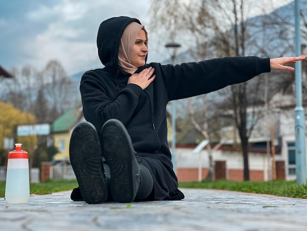 Ein Mädchen mit Hijab trainiert frühmorgens Eine muslimische Frau in Sportkleidung dehnt sich im Freien