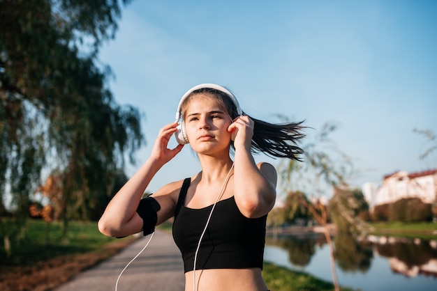 Ein Mädchen mit Kopfhörern beschäftigt sich in einer Metropole mit Outdoor-Fitness. Laufen und Sport im Sommer