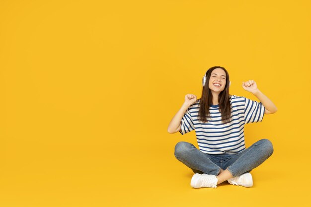 Foto ein mädchen mit kopfhörern hört musik auf einem gelben hintergrund