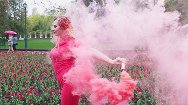 Ein Mädchen mit Make-up mit Regenbogenzöpfen im roten Kleid posiert im roten Kleid