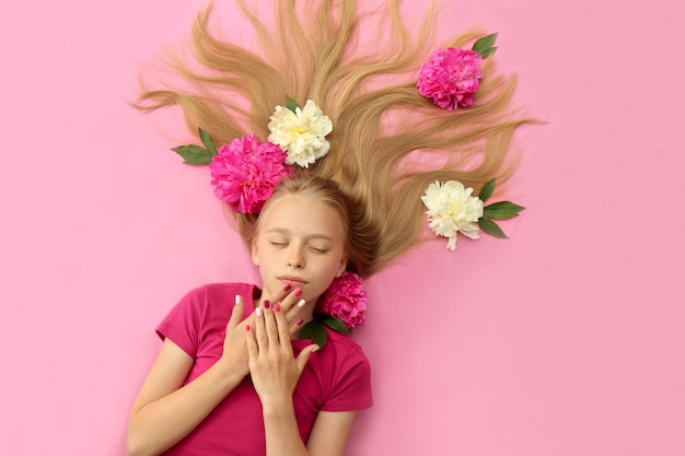 Ein Mädchen mit Pfingstrosen, schönen blonden Haaren und einer bunten Kindermaniküre