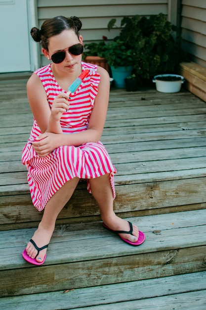 Ein Mädchen mit Sonnenbrille, das ein Eiscreme isst