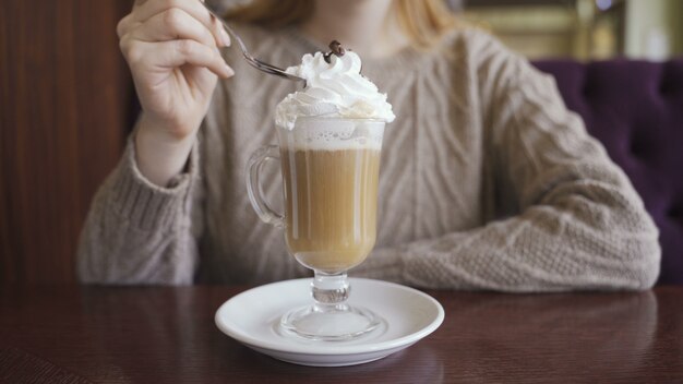 Ein Mädchen nimmt Sahne vom Kaffee mit Löffel