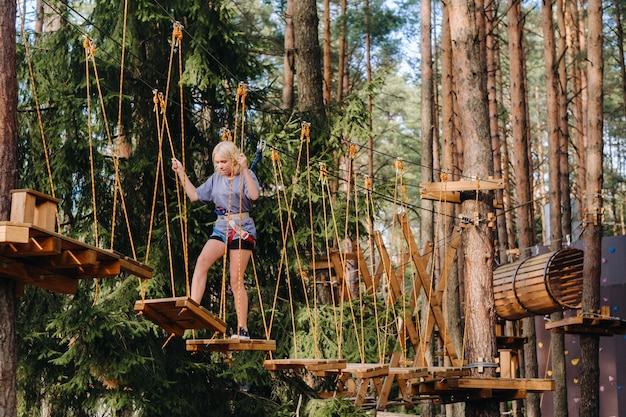 Foto ein mädchen passiert ein hindernis in einer seilstadt. ein mädchen in einem waldseilpark