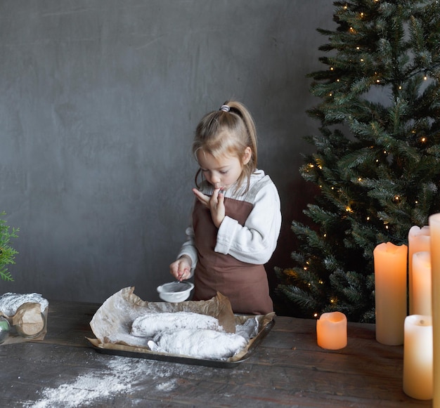 Ein Mädchen probiert Puderzucker, während es ein Weihnachtsgebäck kocht