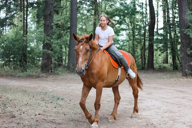 Ein Mädchen reitet im heißen Sommer im Wald auf einem Pferd