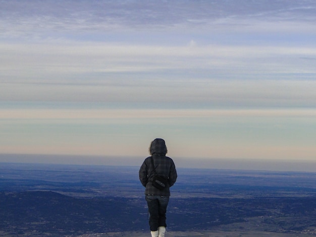 Ein Mädchen schaut von der Spitze des Berges zum Horizont