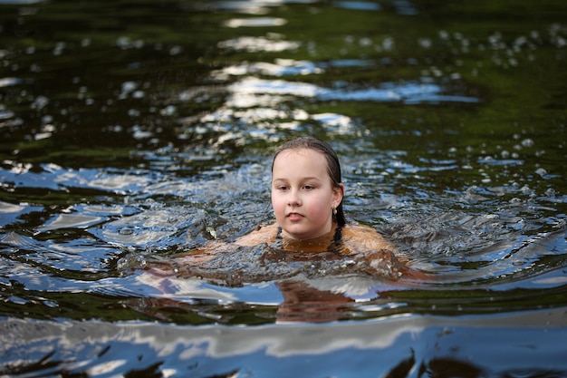 Ein Mädchen schwimmt an einem heißen Sommertag im Fluss