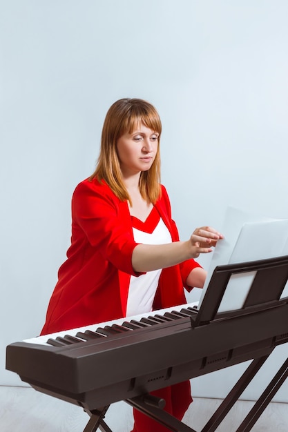 Ein Mädchen sitzt an einem E-Piano und blättert in Notenblättern