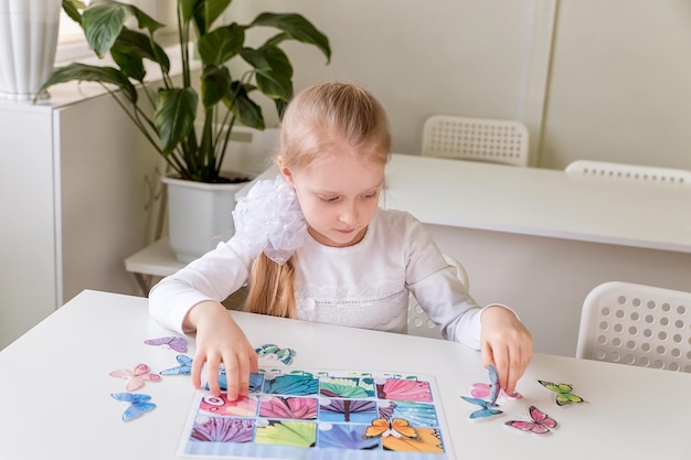 Foto ein mädchen sitzt an einem schreibtisch im klassenzimmer und sammelt figuren, rätsel und kleine spielzeuge