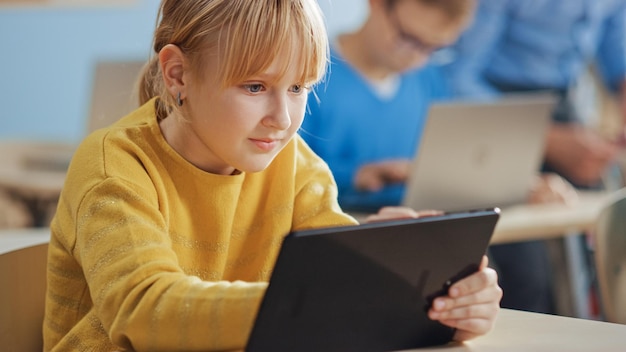 Ein Mädchen sitzt an einem Schreibtisch mit einem Tablet vor sich.