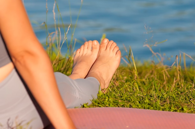 Ein Mädchen sitzt auf dem Gras am Ufer des Sees, Beine in Nahaufnahme