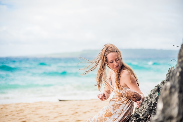 Ein Mädchen sitzt auf einem Felsen am Strand von Boracay