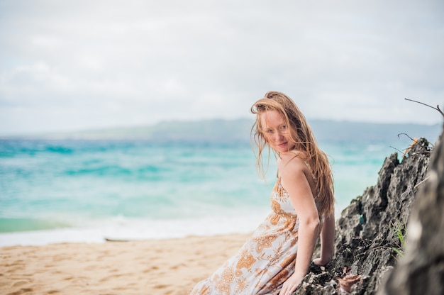 Ein Mädchen sitzt auf einem Felsen am Strand von Boracay