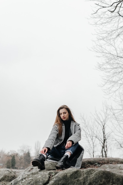 Ein Mädchen sitzt auf einem Felsen vor einem Fluss