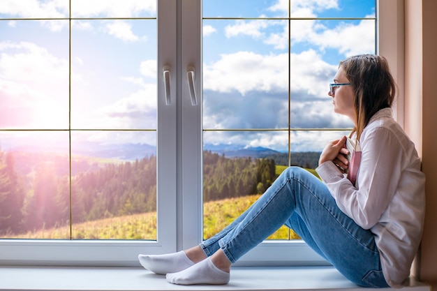 Ein Mädchen sitzt auf einer Fensterbank und schaut aus dem Fenster.