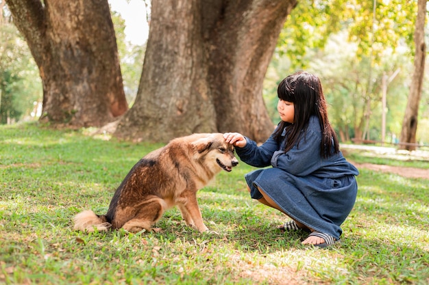 Ein Mädchen sitzt mit einem braunen Hund im Garten