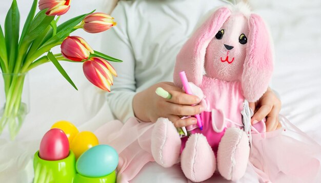 Ein Mädchen sitzt vor einem Osterhasen mit einem Korb voller Ostereier.