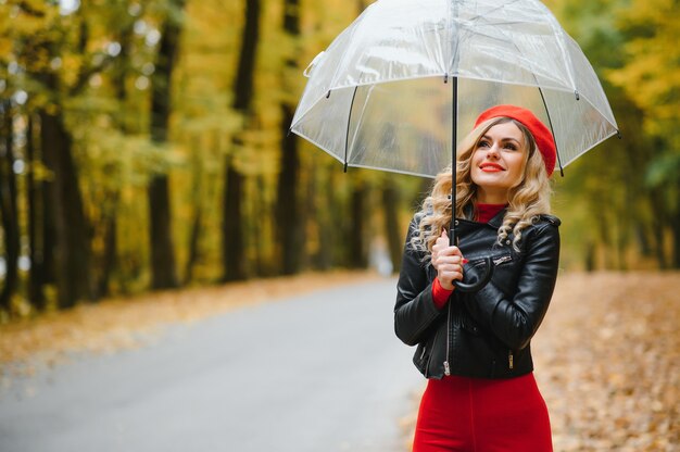 Ein Mädchen spaziert im Herbstpark unter einem Regenschirm