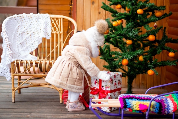 Ein Mädchen steht am Weihnachtstag neben einem Weihnachtsbaum mit vielen Mandarinen