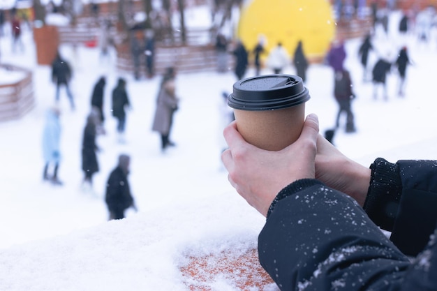 Ein Mädchen trinkt im Winter Kaffee aus einem Pappbecher auf einer offenen Eisbahn in Sevkabel. Sankt Petersburg, Russland