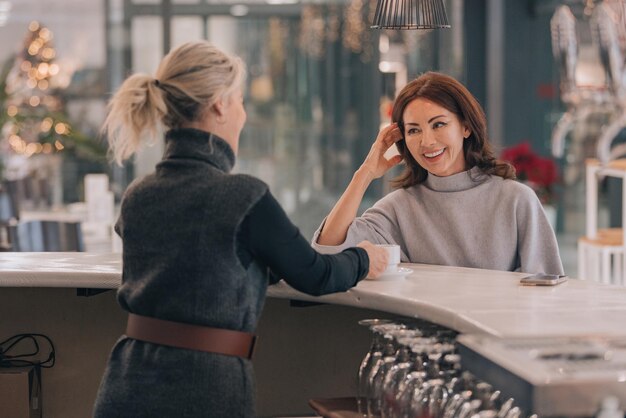 Foto ein mädchen trinkt kaffee an der bar eines cafés und spricht mit der kellnerin