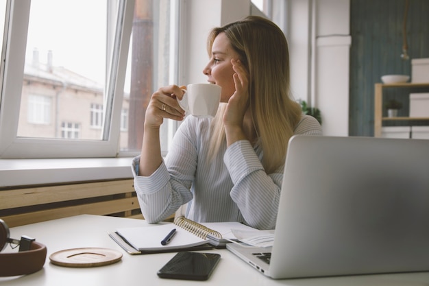 ein Mädchen trinkt Kaffee an ihrem Schreibtisch