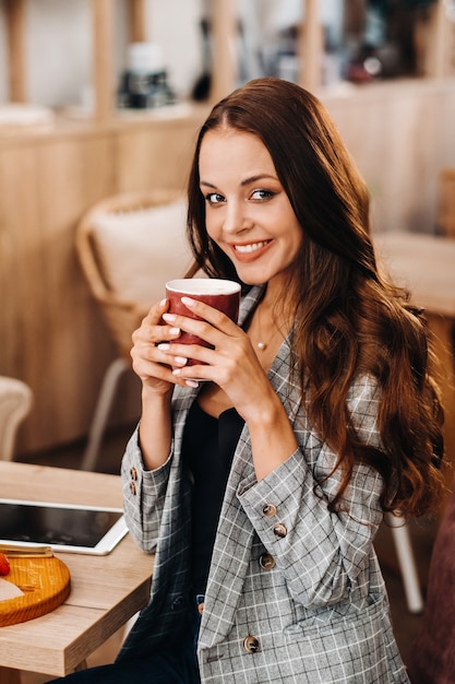 Ein Mädchen trinkt Kaffee in einem Café, schöne Haare eines Mädchens.