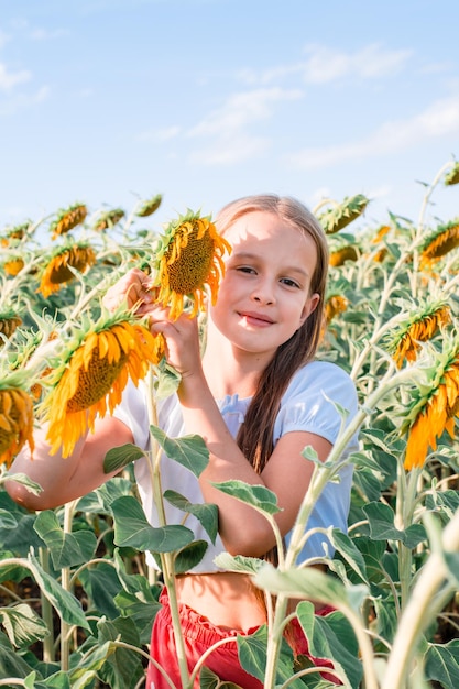 Ein Mädchen umarmt eine Sonnenblume auf einem Feld in der Sonne Anbau und Ernte