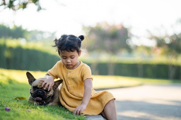 Ein Mädchen und ein Hund sitzen im Gras.