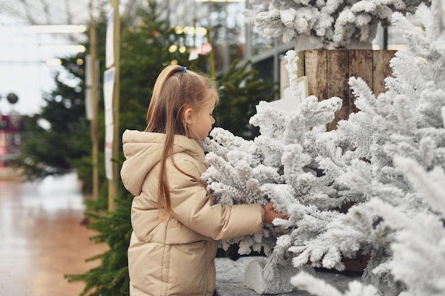 Ein Mädchen und ein künstlicher Weihnachtsbäume zum Verkauf in einem Geschäft