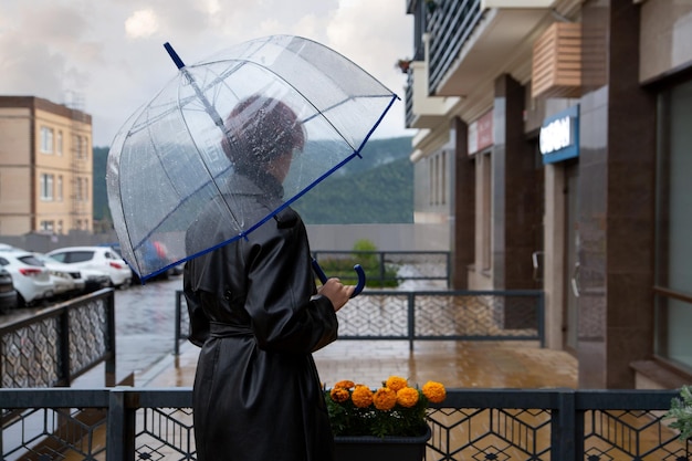 Ein Mädchen unter einem transparenten Regenschirm steht im Regen auf einer Stadtstraße.