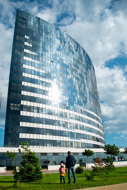 Ein Mädchen vor einem großen, modernen Gebäude vor blauem Himmel Moderne Architektur Leben in der Stadt