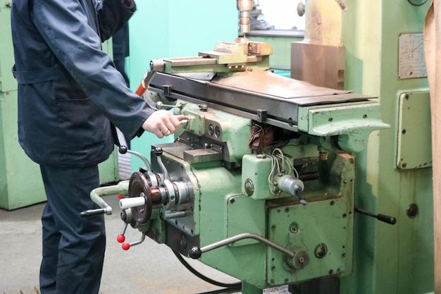 Ein männlicher Arbeiter arbeitet an einer größeren Drehmaschine aus Metalleisen für Reparaturen von Metallarbeiten