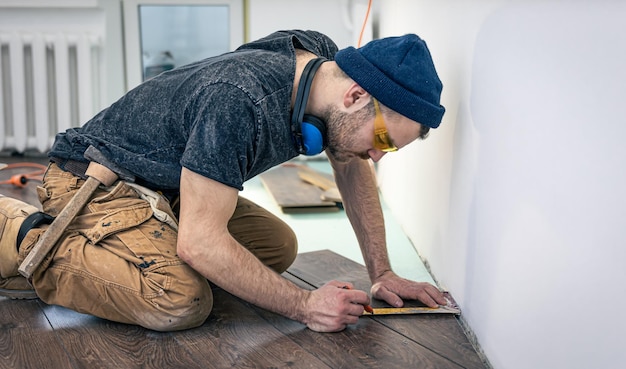 Ein männlicher Arbeiter legt Laminatboden auf den Boden