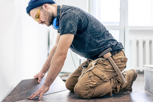 Ein männlicher Arbeiter legt Laminatboden auf den Boden